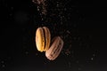 Two macaroons levitate with cocoa powder on a black background