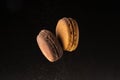 Two macaroons levitate with cocoa powder on a black background