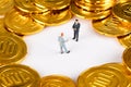 Two macro dolls negotiating in golden coins Royalty Free Stock Photo