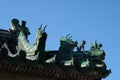 green statues sitting on top of a building with blue sky behind them