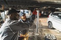 Two male auto mechanics working under the car on a lift in service shop Royalty Free Stock Photo