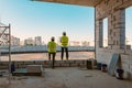 Two male builders at a construction site. Men looking into the distance to the panorama of the city. Building, development, teamwo