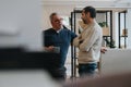 Two professional men engaging in a casual conversation in a modern office Royalty Free Stock Photo