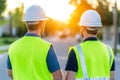 Two male construction workers in safety gear on site at sunset Royalty Free Stock Photo