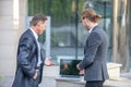 Two male coworkers checking laptop outside, discussing business issues