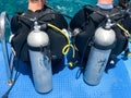 Two male divers in black diving waterproof suits with shiny metal aluminum canisters are preparing to dive from the boat to the bl Royalty Free Stock Photo