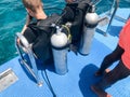 Two male divers in black diving waterproof suits with shiny metal aluminum canisters are preparing to dive from the boat to the bl