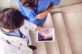 Two Male Doctors Having Informal Meeting In Modern Hospital Looking At X Ray On Digital Tablet Royalty Free Stock Photo