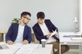 Two male employees sitting at office desks and looking at some business documents Royalty Free Stock Photo