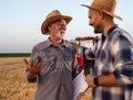 Two male farmers standing in harvested field talking in front of tractor Royalty Free Stock Photo