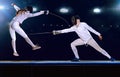 Two fencing athletes fight on professional sports arena