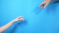 Two male and female hands reaching out to each other, almost touching, on a blue background