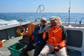 Two male fishermen sit on a boat and drink beer on vacation. Adult leisure lifestyle Royalty Free Stock Photo