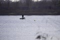 Two male fishermen in warm clothes on a boat, winter fishing on a river or lake. Photo through dry, brown reeds or grass