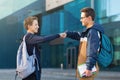 Two male friends meeting oudoors, teenagers greeting each other