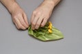 Two male hands hold a wavy decorative element and yellow flowers