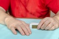 Two male hands hold a white pulse oximeter on a light turquoise