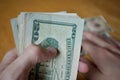 Two male hands holding a set of paper banknotes (American Dollars, USD) and giving the money on the wooden table Royalty Free Stock Photo