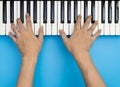 Two male hands playing on music keyboard on blue