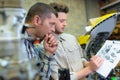 two male mechanics looking at exploded-view drawing