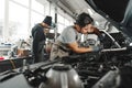 Two male mechanics repairing car in car service close up