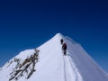 Two male mountain climbers on an exposed snow summit ridge in the Swiss Alps Royalty Free Stock Photo