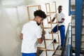 Two Male Movers Carrying The Empty Shelf At Home Royalty Free Stock Photo