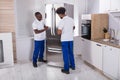 Two Male Movers Fixing The Freezer In The Kitchen