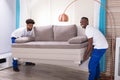 Two Male Movers Placing The Sofa Royalty Free Stock Photo