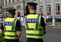 Two male police officers in hi-visibility jacket witnessing the crowd