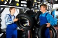 Two male professionals standing with new tires Royalty Free Stock Photo