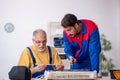 Two male repairmen repairing air-conditioner