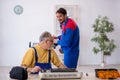 Two male repairmen repairing air-conditioner