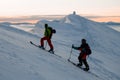 two male skiers climb up to the top of a snowy mountain slope