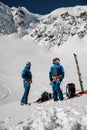 two male skiers in ski suits and helmets stand against the backdrop of a snow-covered mountain slope. Royalty Free Stock Photo