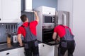 Two Male Technician Fixing The Home Appliances In Kitchen