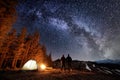 Two male tourists have a rest in the camping near the forest at night under night sky full of stars and milky way Royalty Free Stock Photo