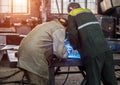 Two male workers at the factory welder and his assistant weld parts welding, sunset, workshop, welder