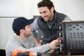 two male workers fixing oven in kitchen Royalty Free Stock Photo