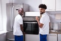 Two Male Workers Placing The Oven In The Kitchen Royalty Free Stock Photo