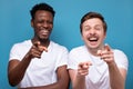 Two man african american and caucasian pointing at camera with index finger and laughing out loud Royalty Free Stock Photo