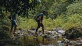 two man crossing a small river in the rainforest jungle Royalty Free Stock Photo