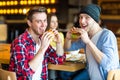 Two man eating burger. Young girl and young man are holding burgers on hands