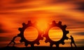 Two Man Pushing Gears At Sunset Orange sky. Businessmen Collaborate Together to Connect The Cogwheels. Royalty Free Stock Photo