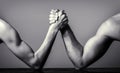 Two man`s hands clasped arm wrestling, strong and weak, unequal match. Arm wrestling. Heavily muscled man arm wrestling