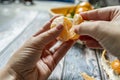 two man's hands separating a segment of ripe tangerine and in the background a basket