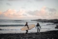 Two man and woman surfers with the surf boards walking on the sea shore Royalty Free Stock Photo