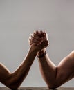 Two man& x27;s hands clasped arm wrestling, strong and weak, unequal match. Heavily muscled man arm wrestling a puny weak