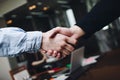 Two managers in casual clothing in meeting room handshakes after finding compromise