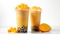 Two mango bubble tea drinks with tapioca pearls and fruit chunks sit on a white surface. A halved mango fruit rests nearby. These Royalty Free Stock Photo
